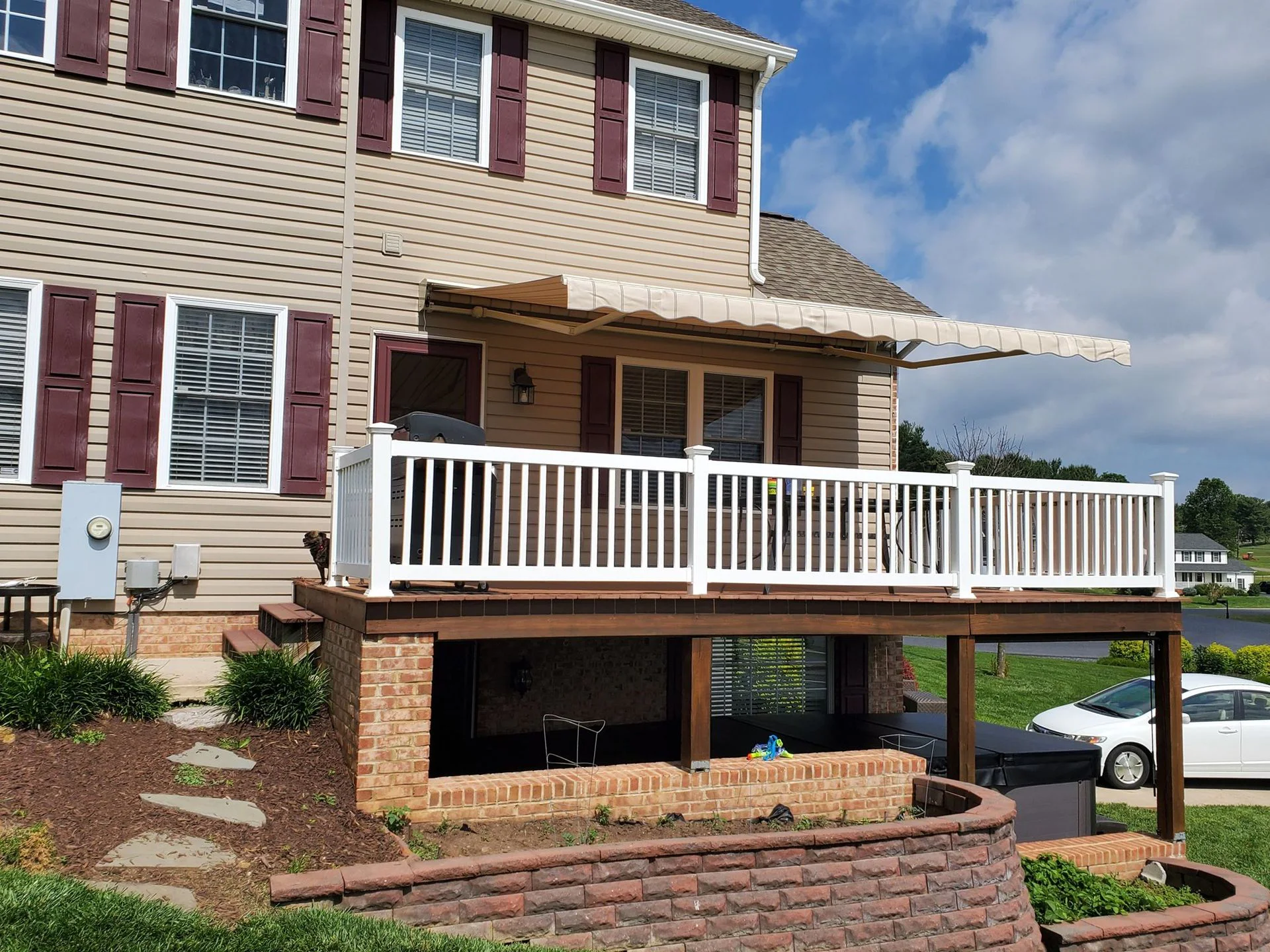 Two-story home with a white deck under a retractable awning