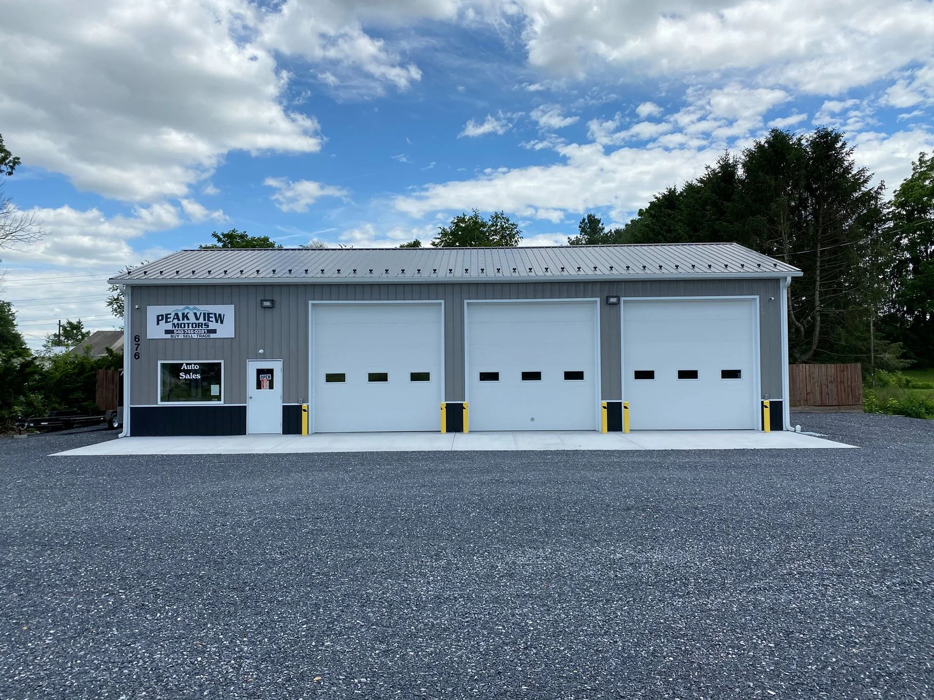 Gray auto repair shop with three white overhead doors